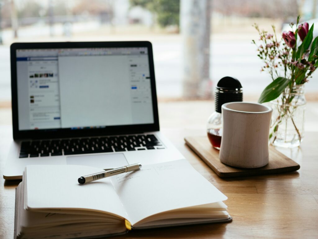 Bureau lumineux avec ordinateur, carnet et stylo, illustrant le travail rédactionnel d'une rédactrice freelance. Scène de stratégie de contenu et d'écriture.